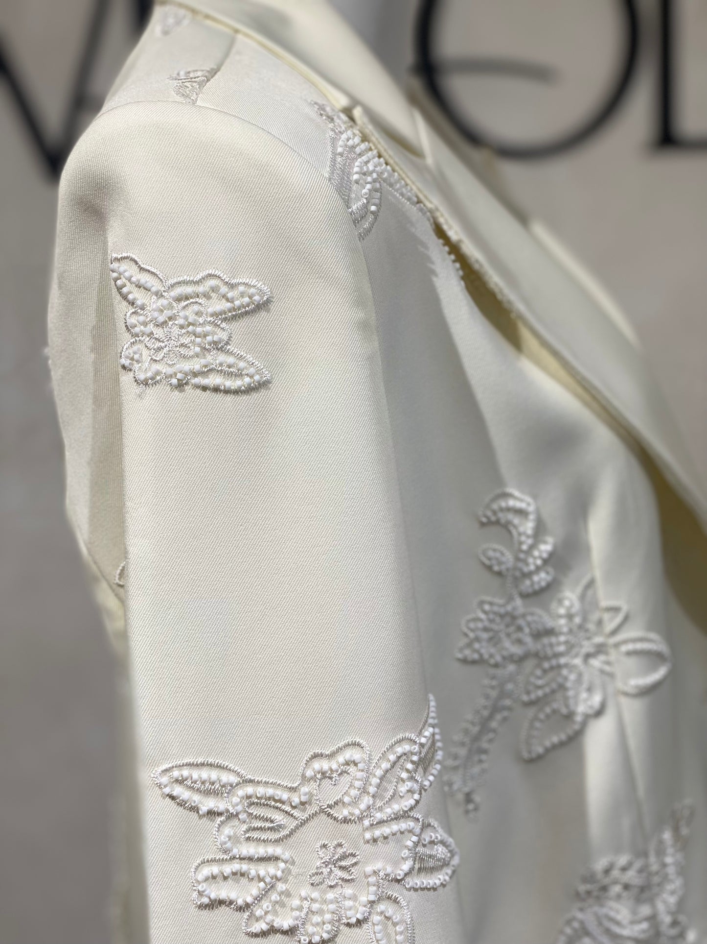 Découvrez la veste perlée Amira, un blazer blanc cassé d'exception orné de perles blanches de haute qualité. Son unique bouton apporte une touche d’élégance raffinée, parfaite pour sublimer vos tenues lors d’événements prestigieux. Cette pièce allie sophistication et style intemporel, garantissant une allure distinguée en toutes circonstances.
