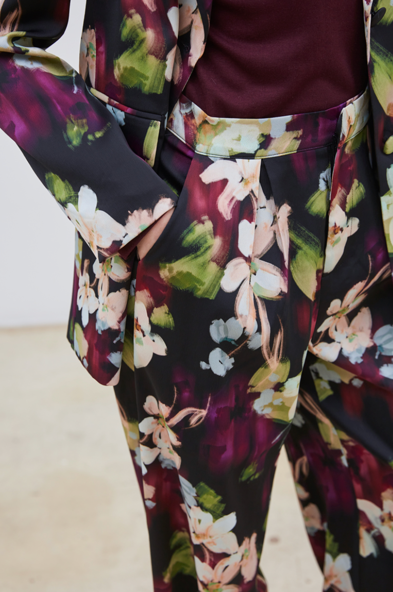 Le pantalon Flora séduit par son motif floral délicat aux nuances de mauve, bleu ciel, vert clair et beige, posé sur un fond noir élégant. Confectionné dans un tissu de qualité, il assure une allure chic et sophistiquée. Polyvalent, il s’adapte parfaitement porté seul ou accompagné de son blazer assorti, pour un ensemble harmonieux et raffiné.