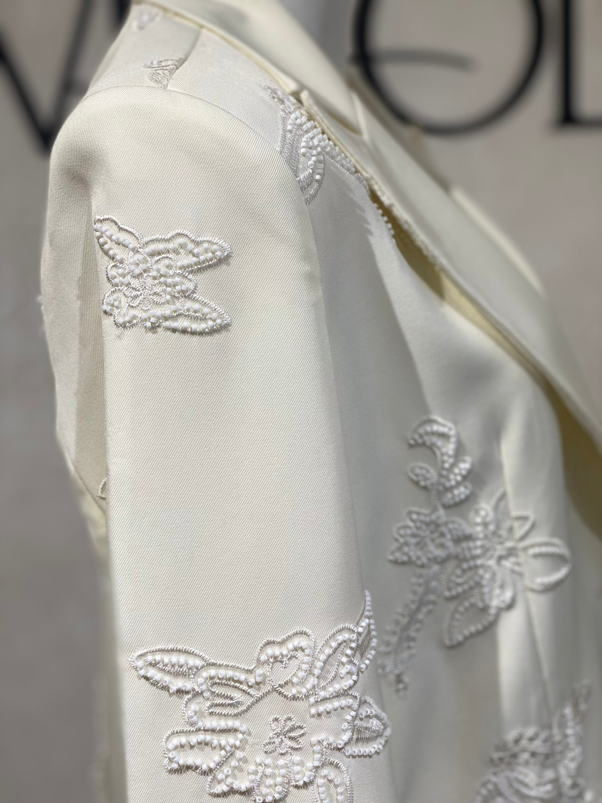 Découvrez la veste perlée Amira, un blazer blanc cassé d'exception orné de perles blanches de haute qualité. Son unique bouton apporte une touche d’élégance raffinée, parfaite pour sublimer vos tenues lors d’événements prestigieux. Cette pièce allie sophistication et style intemporel, garantissant une allure distinguée en toutes circonstances.