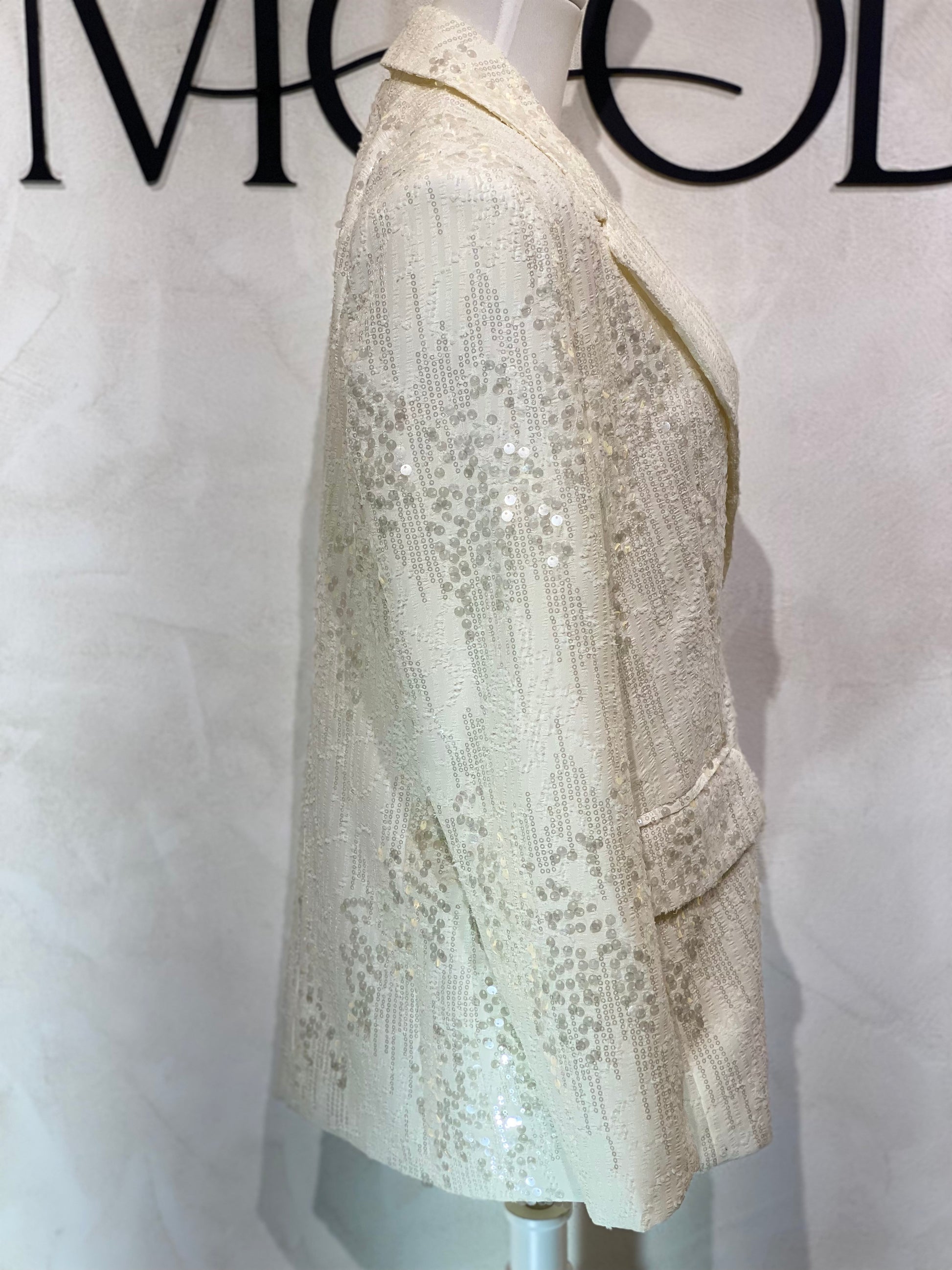 Le blazer Mira en blanc nacré, richement recouvert de paillettes, offre une silhouette élégante sublimée par sa coupe sophistiquée. Doté de deux boutons, il incarne la pièce idéale pour rehausser vos tenues lors d’événements, alliant raffinement et modernité pour une allure impeccable.