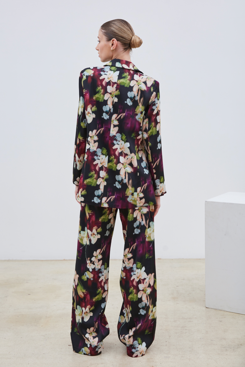 La veste Flora allie élégance et originalité avec ses motifs floraux abstraits aux nuances subtiles de beige, violet, bleu ciel et vert sur un fond noir profond. Sa coupe chic est sublimée par une ceinture et deux boutons délicats, apportant une touche raffinée et structurée. Parfaite pour affirmer un style sophistiqué tout en restant tendance.