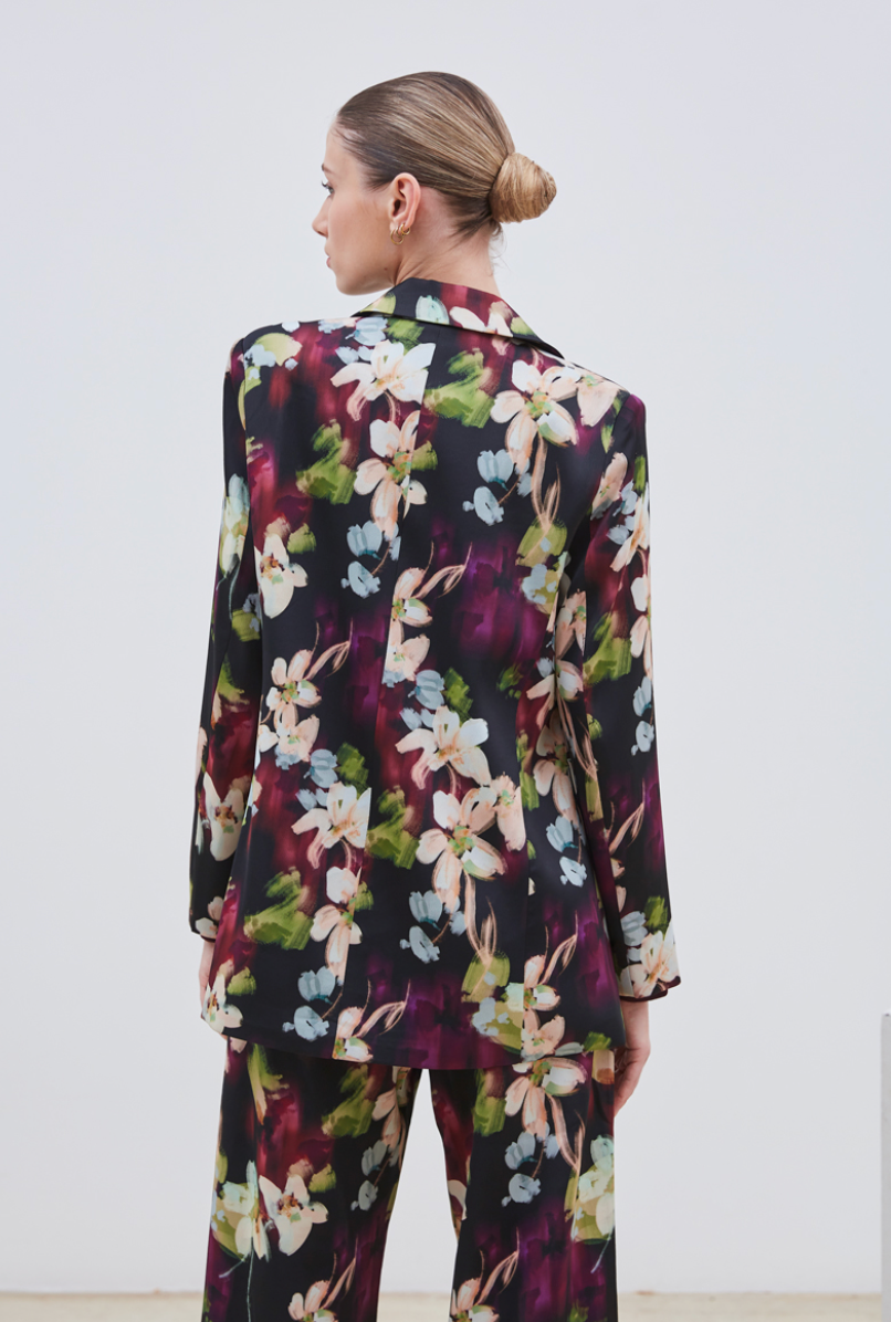 La veste Flora allie élégance et originalité avec ses motifs floraux abstraits aux nuances subtiles de beige, violet, bleu ciel et vert sur un fond noir profond. Sa coupe chic est sublimée par une ceinture et deux boutons délicats, apportant une touche raffinée et structurée. Parfaite pour affirmer un style sophistiqué tout en restant tendance.