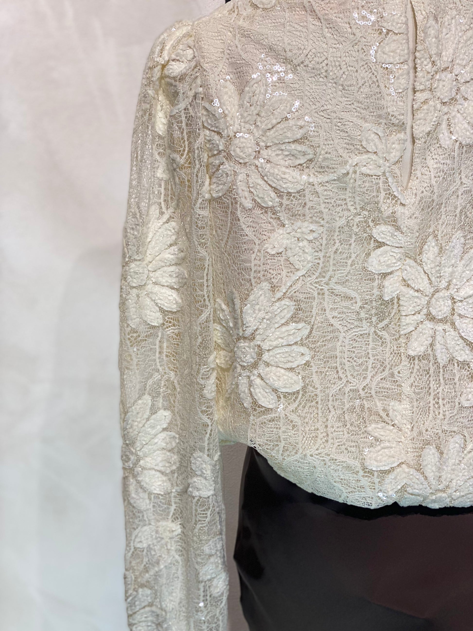 Le Haut Sandra allie élégance et modernité avec son col rond sophistiqué et sa délicate broderie en dentelle blanc nacré. Ses manches transparentes offrent une touche de légèreté, tandis que la finition impeccable garantit un look chic et raffiné. Idéal pour celles qui souhaitent se démarquer avec style et délicatesse.