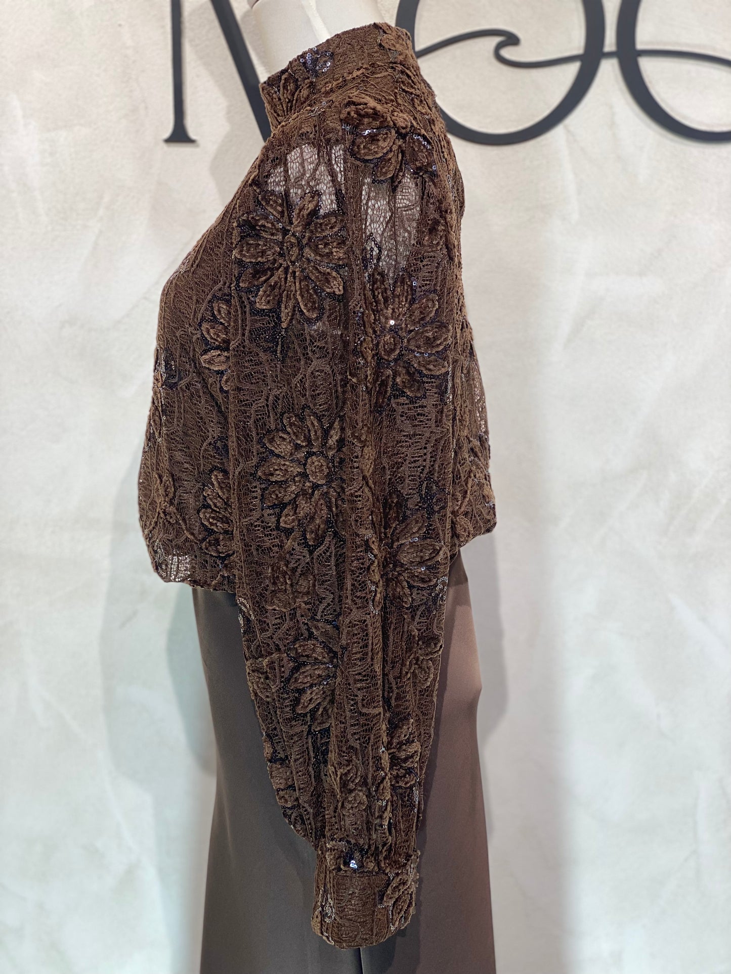 Le Haut Sandra allie élégance et modernité avec son col rond sophistiqué et sa délicate broderie en dentelle blanc nacré. Ses manches transparentes offrent une touche de légèreté, tandis que la finition impeccable garantit un look chic et raffiné. Idéal pour celles qui souhaitent se démarquer avec style et délicatesse.
