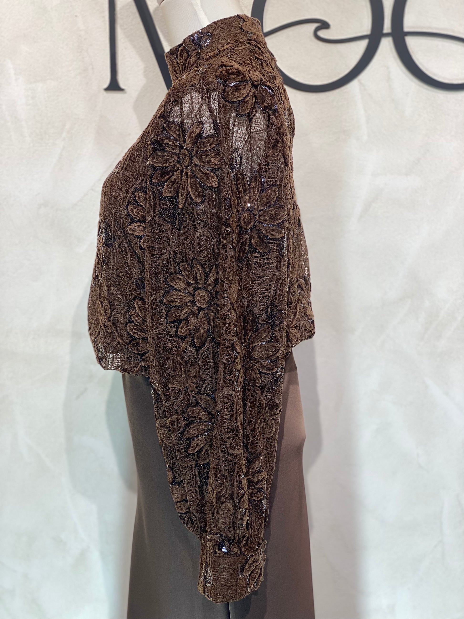 Le Haut Sandra allie élégance et modernité avec son col rond sophistiqué et sa délicate broderie en dentelle blanc nacré. Ses manches transparentes offrent une touche de légèreté, tandis que la finition impeccable garantit un look chic et raffiné. Idéal pour celles qui souhaitent se démarquer avec style et délicatesse.