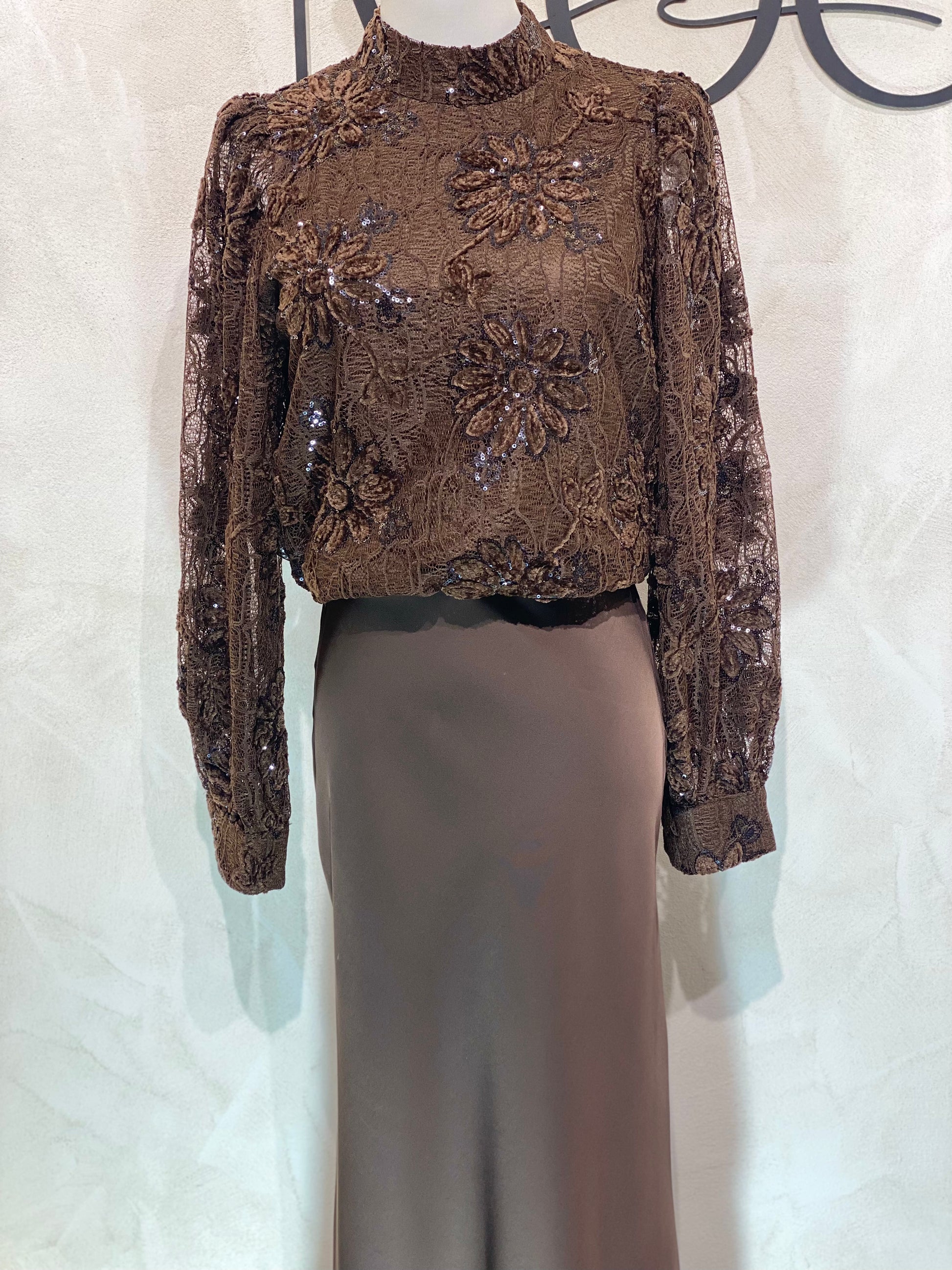Le Haut Sandra allie élégance et modernité avec son col rond sophistiqué et sa délicate broderie en dentelle blanc nacré. Ses manches transparentes offrent une touche de légèreté, tandis que la finition impeccable garantit un look chic et raffiné. Idéal pour celles qui souhaitent se démarquer avec style et délicatesse.