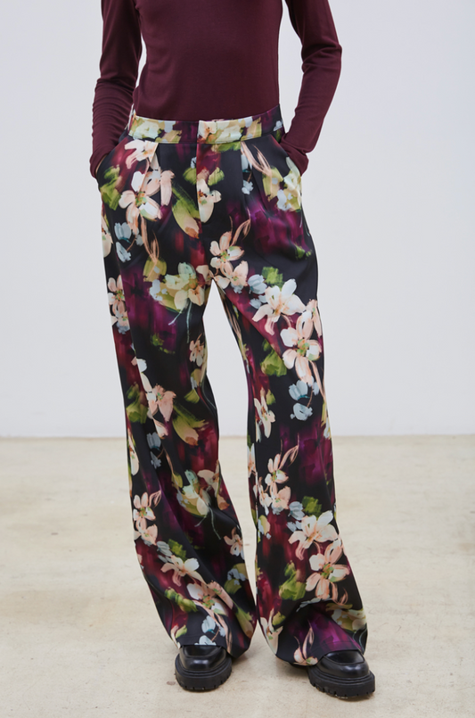 Le pantalon Flora séduit par son motif floral délicat aux nuances de mauve, bleu ciel, vert clair et beige, posé sur un fond noir élégant. Confectionné dans un tissu de qualité, il assure une allure chic et sophistiquée. Polyvalent, il s’adapte parfaitement porté seul ou accompagné de son blazer assorti, pour un ensemble harmonieux et raffiné.