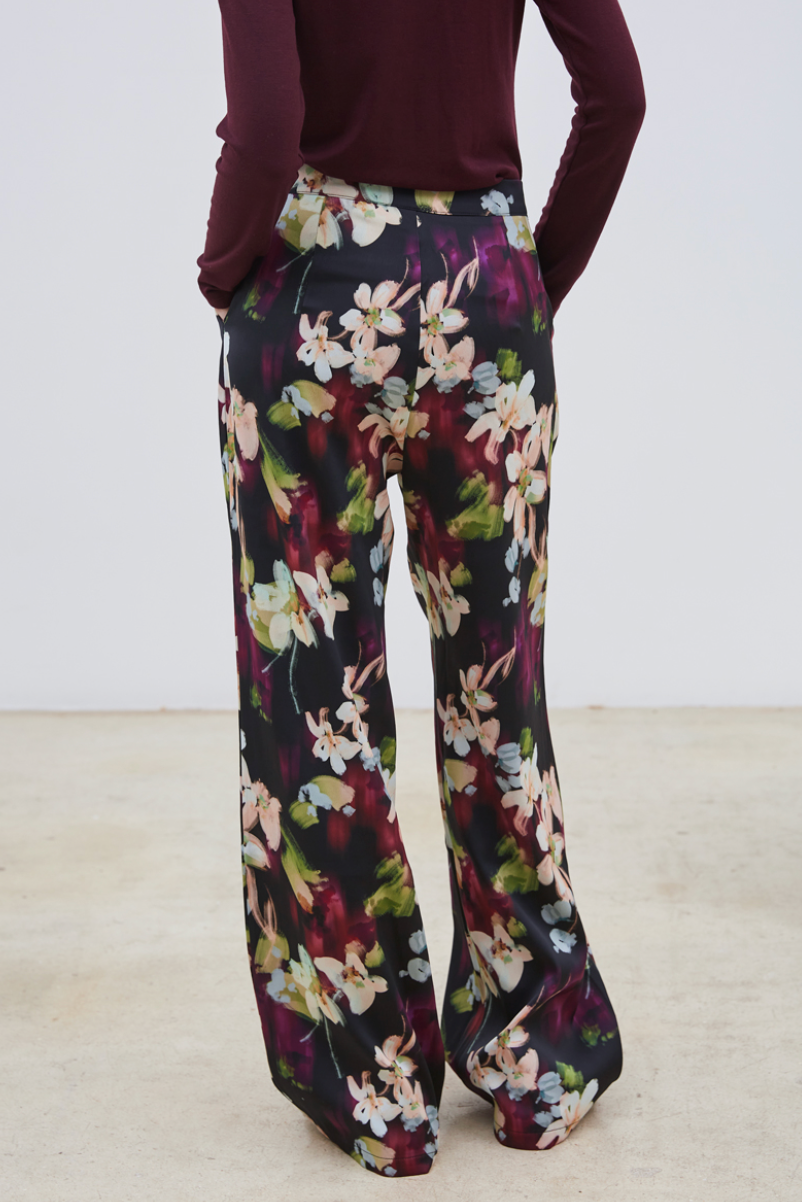 Le pantalon Flora séduit par son motif floral délicat aux nuances de mauve, bleu ciel, vert clair et beige, posé sur un fond noir élégant. Confectionné dans un tissu de qualité, il assure une allure chic et sophistiquée. Polyvalent, il s’adapte parfaitement porté seul ou accompagné de son blazer assorti, pour un ensemble harmonieux et raffiné.