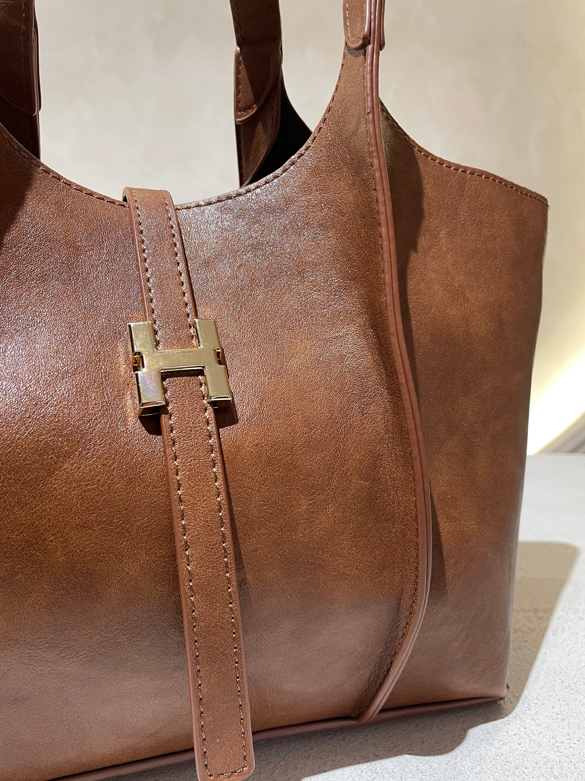 Le sac à main Hadra allie élégance et tendance avec son cuir façon Hermès aux teintes noire, marron et camel. Son design raffiné et ses détails minutieux en font un accessoire classe, parfait pour rehausser votre style. Polyvalent, il peut se porter avec ou sans bandoulière, s’adaptant à toutes vos envies. Adoptez une allure chic et moderne grâce à ce sac incontournable de la saison.