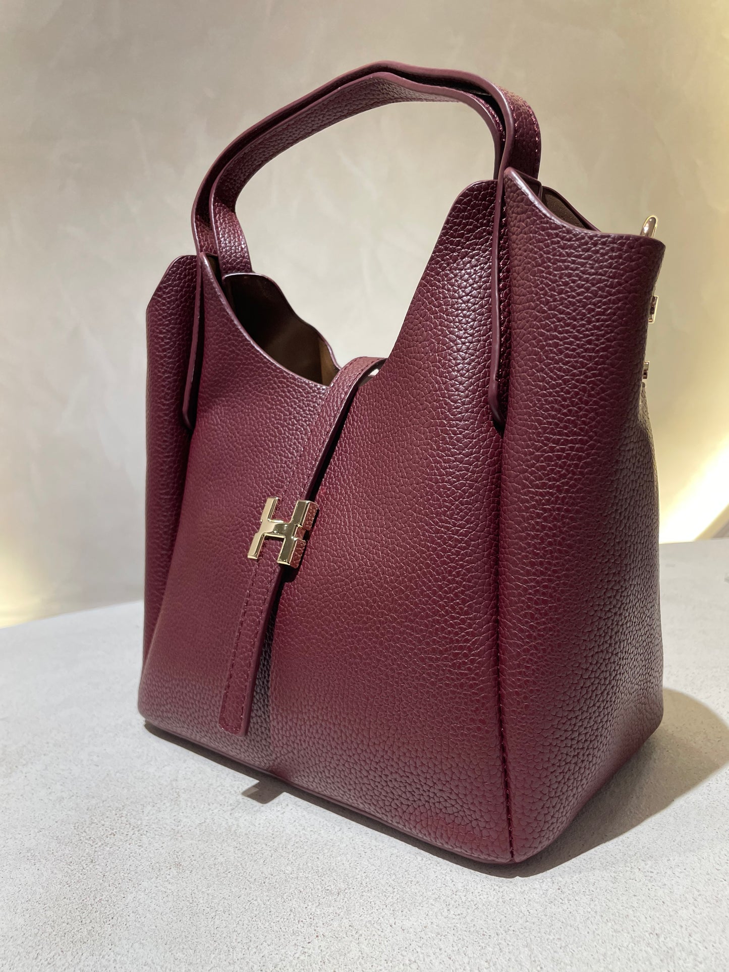 Découvrez le sac à main Hélia, une élégante pièce en simili cuir d'inspiration Hermès qui allie sophistication et raffinement. Disponible en cinq teintes raffinées — bordeaux, taupe, noir, camel et marron — ce sac se distingue par sa silhouette soignée et ses détails minutieux, notamment l’emblématique « H » en acier inoxydable doré. Avec une dimension idéale de 25 x 25 cm et une épaisseur de 14 cm, il offre un équilibre parfait entre style et fonctionnalité. Une bandoulière amovible complète ce modèle pour