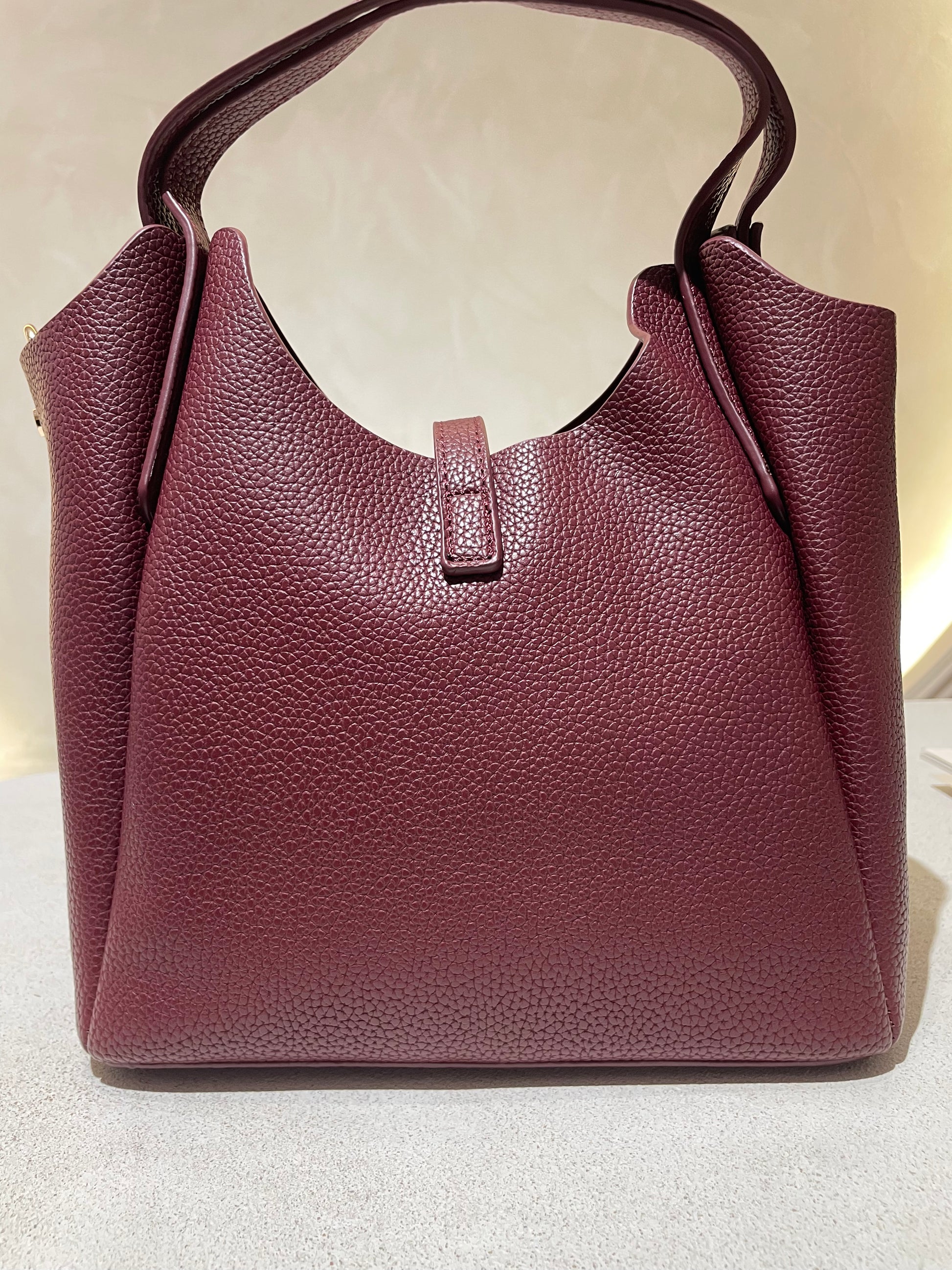 Découvrez le sac à main Hélia, une élégante pièce en simili cuir d'inspiration Hermès qui allie sophistication et raffinement. Disponible en cinq teintes raffinées — bordeaux, taupe, noir, camel et marron — ce sac se distingue par sa silhouette soignée et ses détails minutieux, notamment l’emblématique « H » en acier inoxydable doré. Avec une dimension idéale de 25 x 25 cm et une épaisseur de 14 cm, il offre un équilibre parfait entre style et fonctionnalité. Une bandoulière amovible complète ce modèle pour