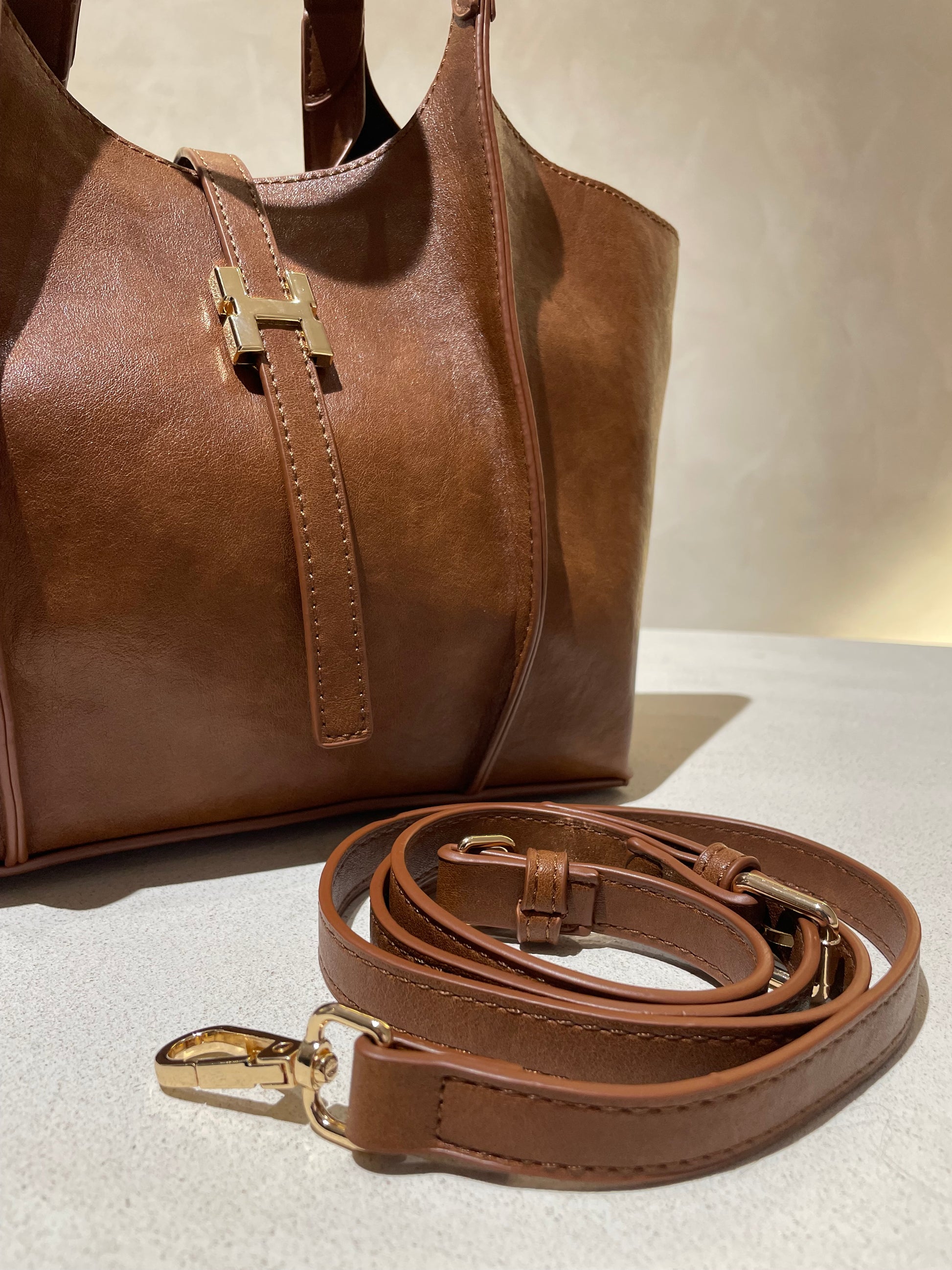 Le sac à main Hadra allie élégance et tendance avec son cuir façon Hermès aux teintes noire, marron et camel. Son design raffiné et ses détails minutieux en font un accessoire classe, parfait pour rehausser votre style. Polyvalent, il peut se porter avec ou sans bandoulière, s’adaptant à toutes vos envies. Adoptez une allure chic et moderne grâce à ce sac incontournable de la saison.
