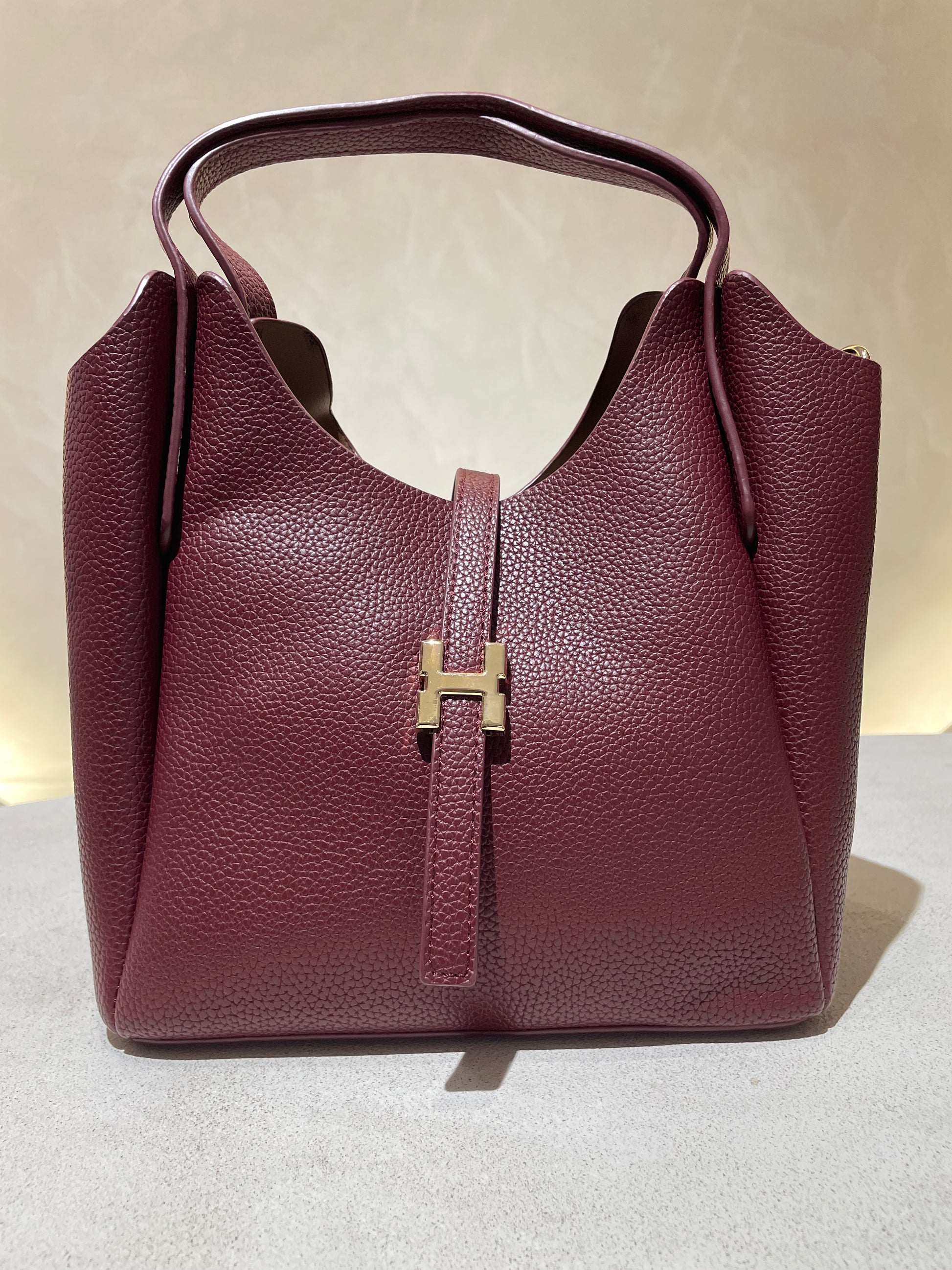 Découvrez le sac à main Hélia, une élégante pièce en simili cuir d'inspiration Hermès qui allie sophistication et raffinement. Disponible en cinq teintes raffinées — bordeaux, taupe, noir, camel et marron — ce sac se distingue par sa silhouette soignée et ses détails minutieux, notamment l’emblématique « H » en acier inoxydable doré. Avec une dimension idéale de 25 x 25 cm et une épaisseur de 14 cm, il offre un équilibre parfait entre style et fonctionnalité. Une bandoulière amovible complète ce modèle pour
