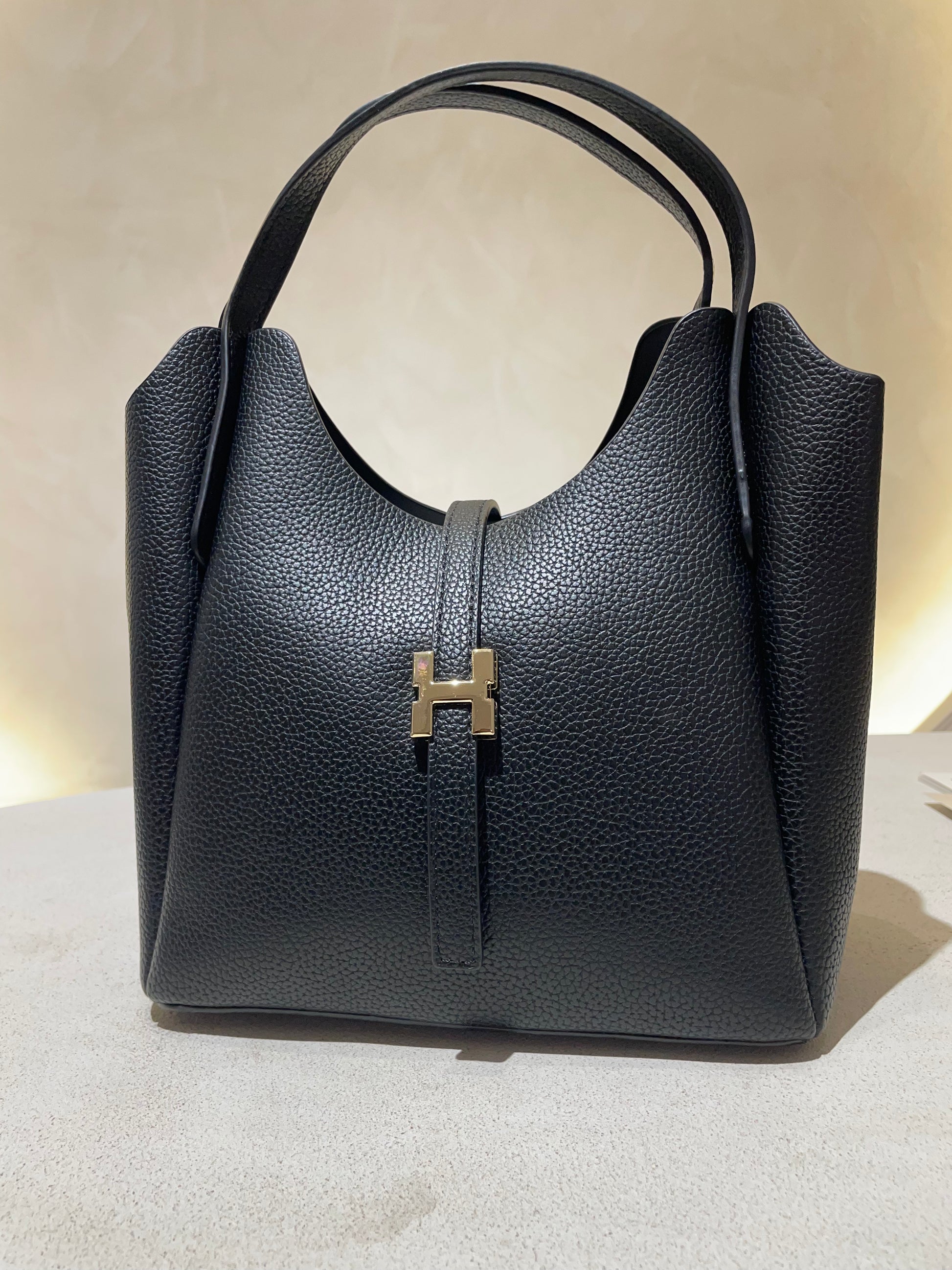 Découvrez le sac à main Hélia, une élégante pièce en simili cuir d'inspiration Hermès qui allie sophistication et raffinement. Disponible en cinq teintes raffinées — bordeaux, taupe, noir, camel et marron — ce sac se distingue par sa silhouette soignée et ses détails minutieux, notamment l’emblématique « H » en acier inoxydable doré. Avec une dimension idéale de 25 x 25 cm et une épaisseur de 14 cm, il offre un équilibre parfait entre style et fonctionnalité. Une bandoulière amovible complète ce modèle pour