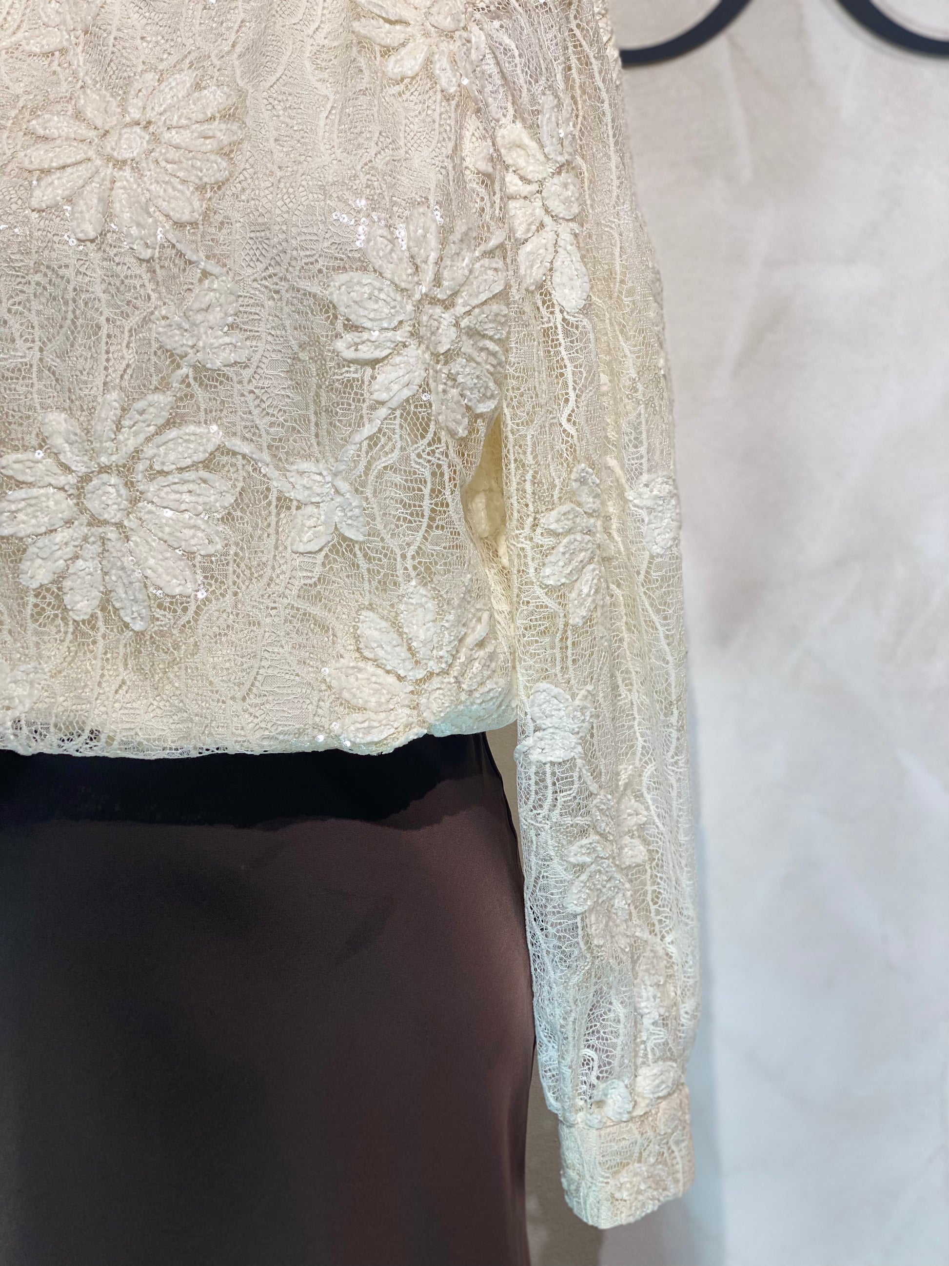 Le Haut Sandra allie élégance et modernité avec son col rond sophistiqué et sa délicate broderie en dentelle blanc nacré. Ses manches transparentes offrent une touche de légèreté, tandis que la finition impeccable garantit un look chic et raffiné. Idéal pour celles qui souhaitent se démarquer avec style et délicatesse.