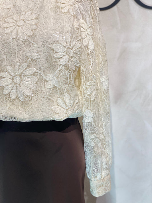Le Haut Sandra allie élégance et modernité avec son col rond sophistiqué et sa délicate broderie en dentelle blanc nacré. Ses manches transparentes offrent une touche de légèreté, tandis que la finition impeccable garantit un look chic et raffiné. Idéal pour celles qui souhaitent se démarquer avec style et délicatesse.