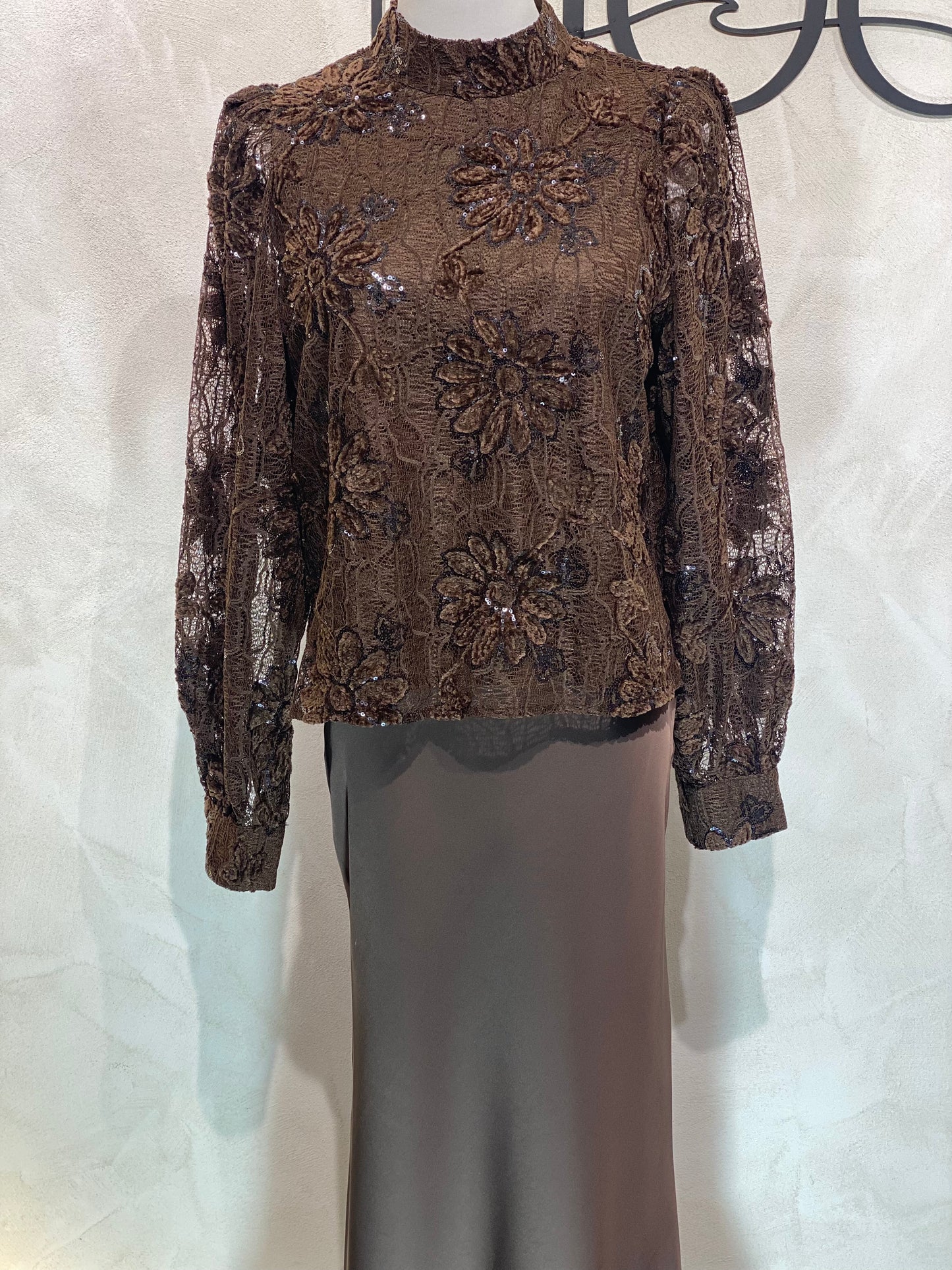 Le Haut Sandra allie élégance et modernité avec son col rond sophistiqué et sa délicate broderie en dentelle blanc nacré. Ses manches transparentes offrent une touche de légèreté, tandis que la finition impeccable garantit un look chic et raffiné. Idéal pour celles qui souhaitent se démarquer avec style et délicatesse.