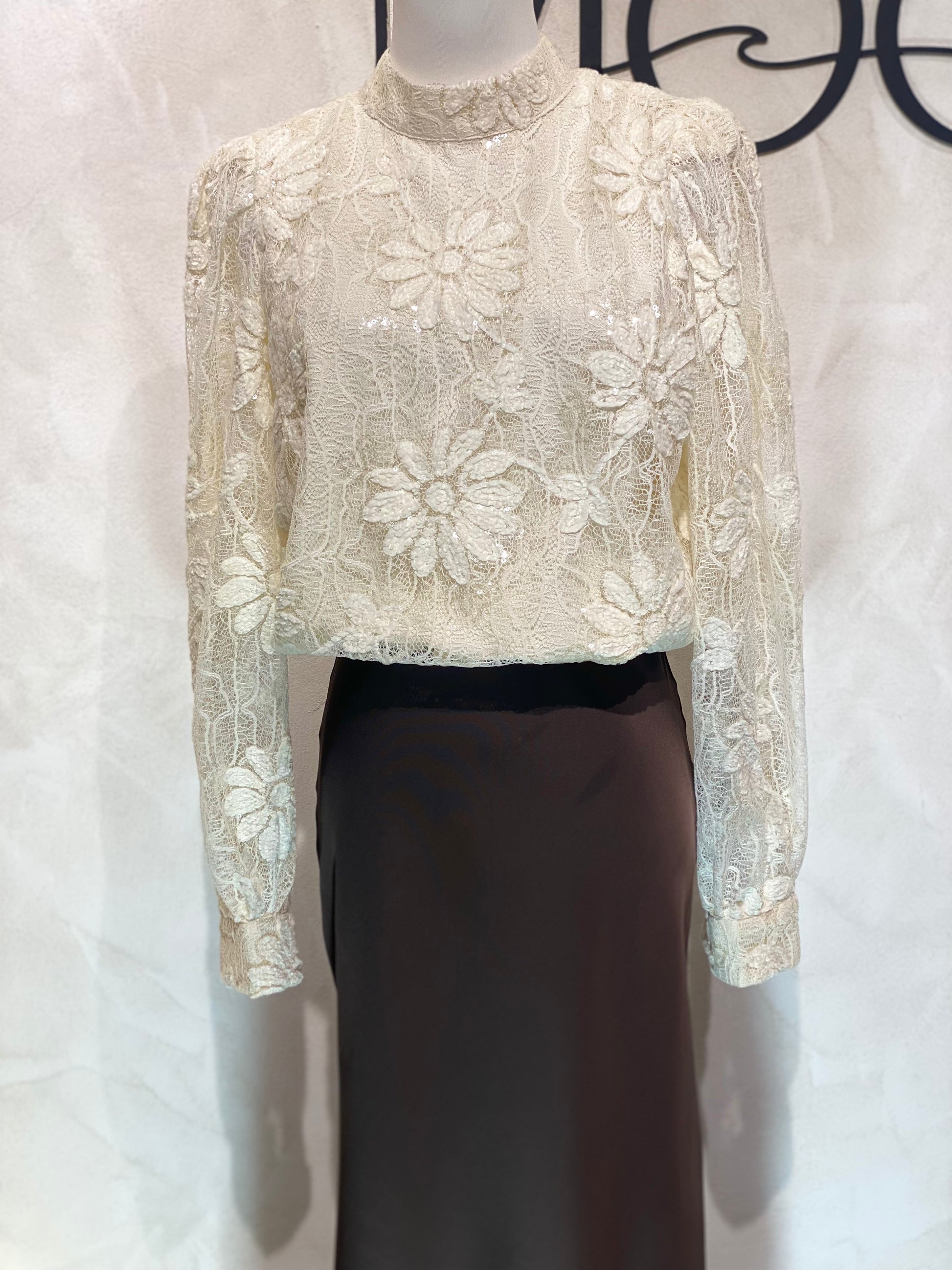 Le Haut Sandra allie élégance et modernité avec son col rond sophistiqué et sa délicate broderie en dentelle blanc nacré. Ses manches transparentes offrent une touche de légèreté, tandis que la finition impeccable garantit un look chic et raffiné. Idéal pour celles qui souhaitent se démarquer avec style et délicatesse.