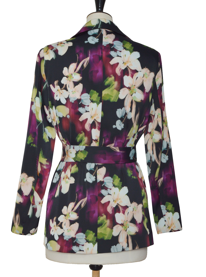 La veste Flora allie élégance et originalité avec ses motifs floraux abstraits aux nuances subtiles de beige, violet, bleu ciel et vert sur un fond noir profond. Sa coupe chic est sublimée par une ceinture et deux boutons délicats, apportant une touche raffinée et structurée. Parfaite pour affirmer un style sophistiqué tout en restant tendance.