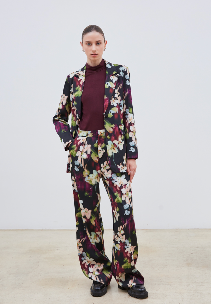La veste Flora allie élégance et originalité avec ses motifs floraux abstraits aux nuances subtiles de beige, violet, bleu ciel et vert sur un fond noir profond. Sa coupe chic est sublimée par une ceinture et deux boutons délicats, apportant une touche raffinée et structurée. Parfaite pour affirmer un style sophistiqué tout en restant tendance.